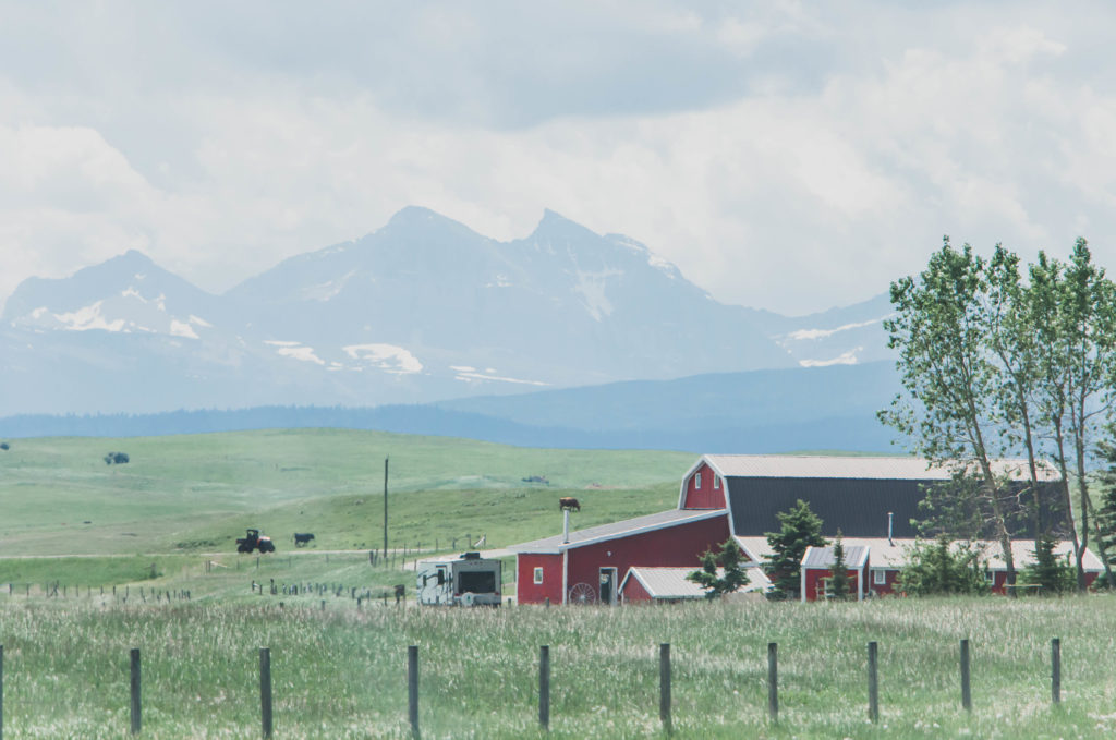 Red barn and farm in front of mountains in Alberta, Canada