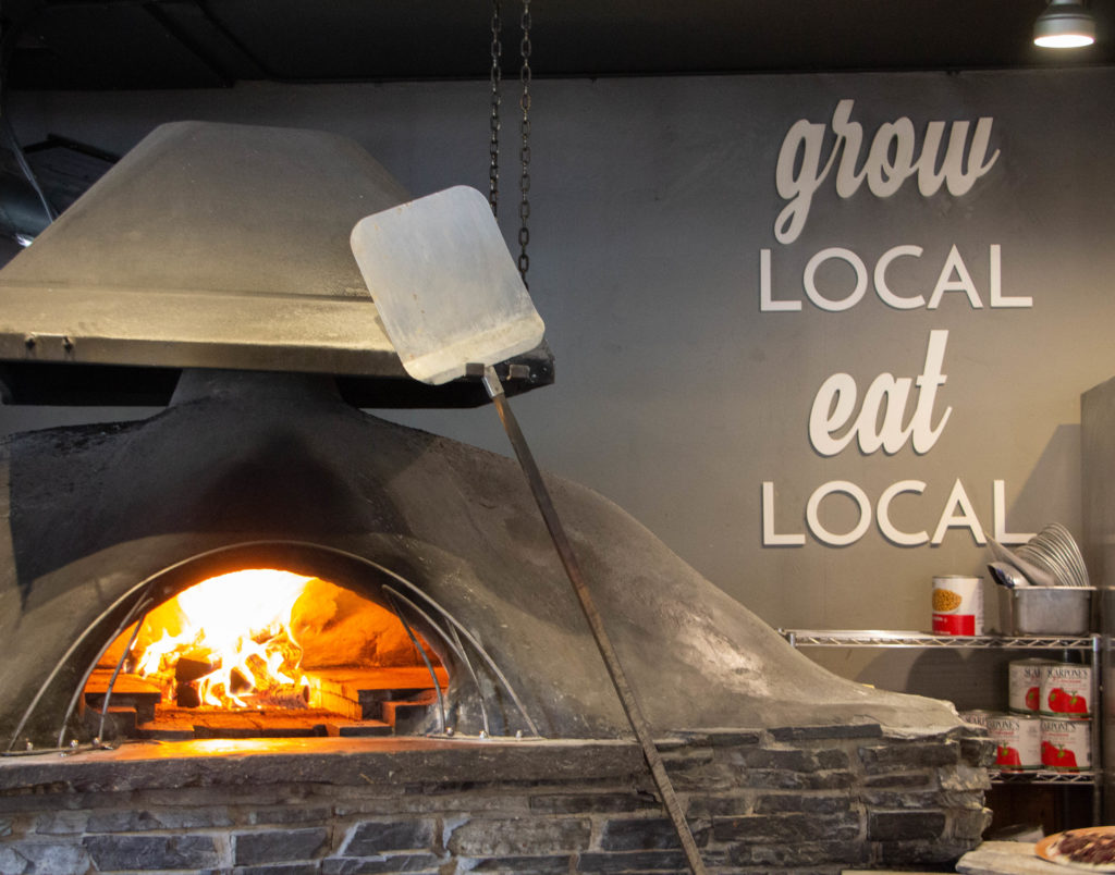 Grow local eat local sign and pizza oven in rocky mountain flatbread co. canmore
