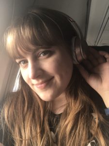 Girl with red hair wearing rose gold beats studio 3 wireless headphones on airplane