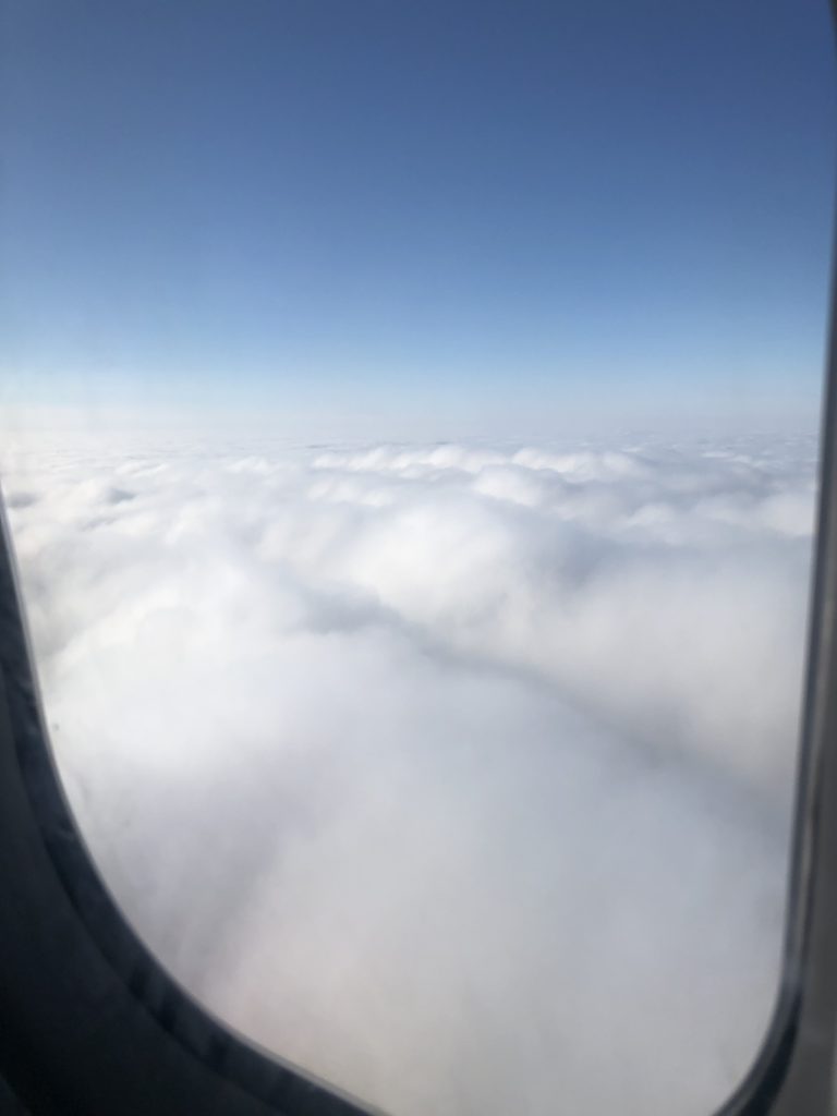 blue sky and fluffy white clouds outside airplane window