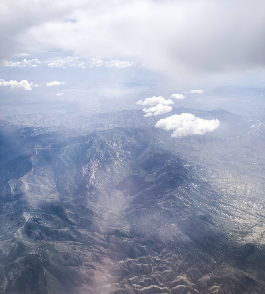 View from airplane of desert mountains in arizona and clouds in blue sky