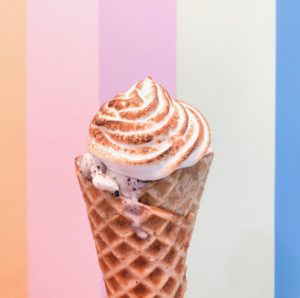torched marshmallow cookies and cream ice cream waffle cone with rainbow stripe background at Wild Scoops in Anchorage alaska