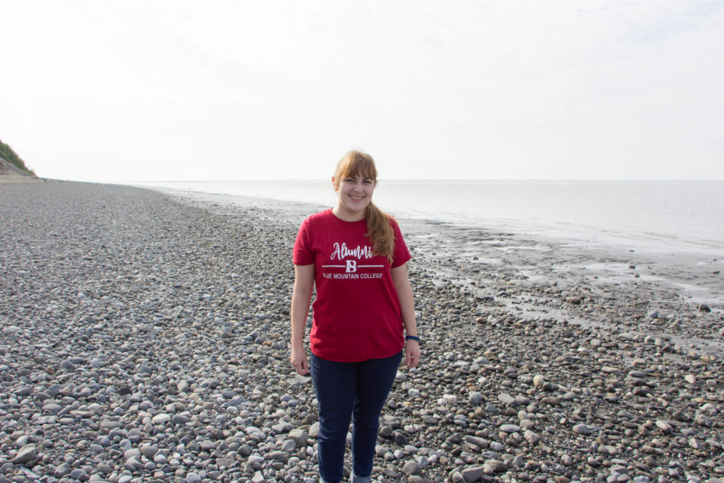 Girl in red tshirt and jeans standing on rocky beach in kincaid anchorage alaska pacific ocean