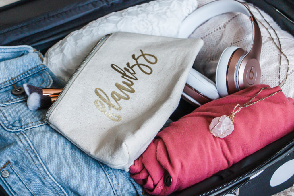 tips for packing a carry on suitcase like a pro flawless make up bag, pink necklace and shirt in luggage