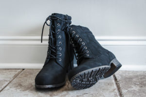 Black lace up hiking boots on tile floor with light walls 