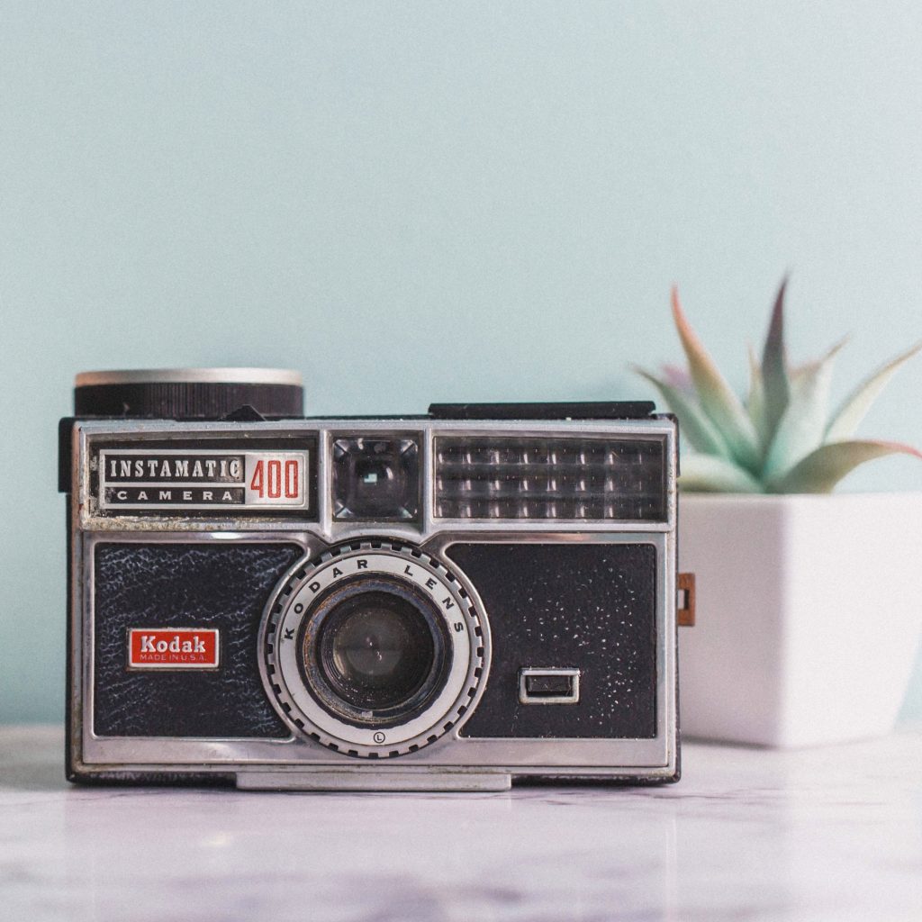 vintage antique kodak instamatic 400 camera on marble surface with blue wall and succulent in white pot