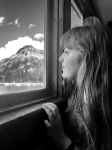 black and white girl looking out window at lake and mountains in Waterton Alberta Canada