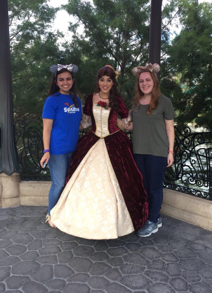 two girls meeting belle from beauty and the beast at epcot in enchanted christmas dress disney world at Christmas time