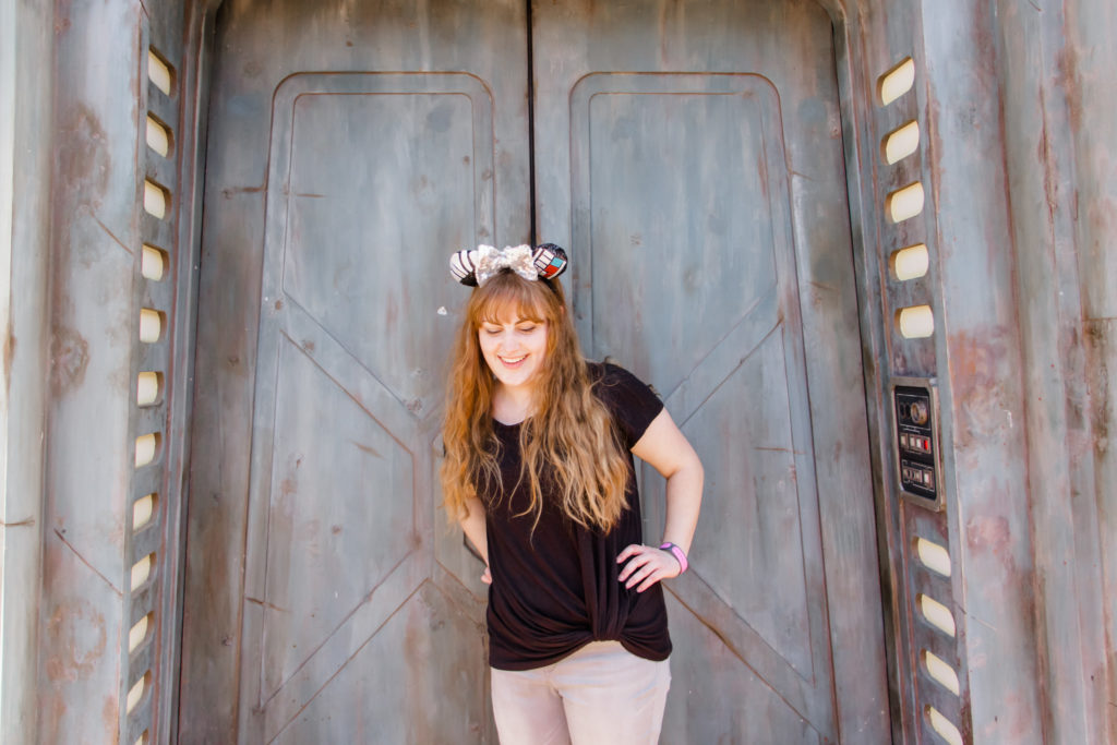 girl in black t shirt and gray pants, Darth Vader Disney bound mickey Minnie ears in front of gray imperial door at Star Wars galaxy's edge Disney World Hollywood Studios Orlando Florida